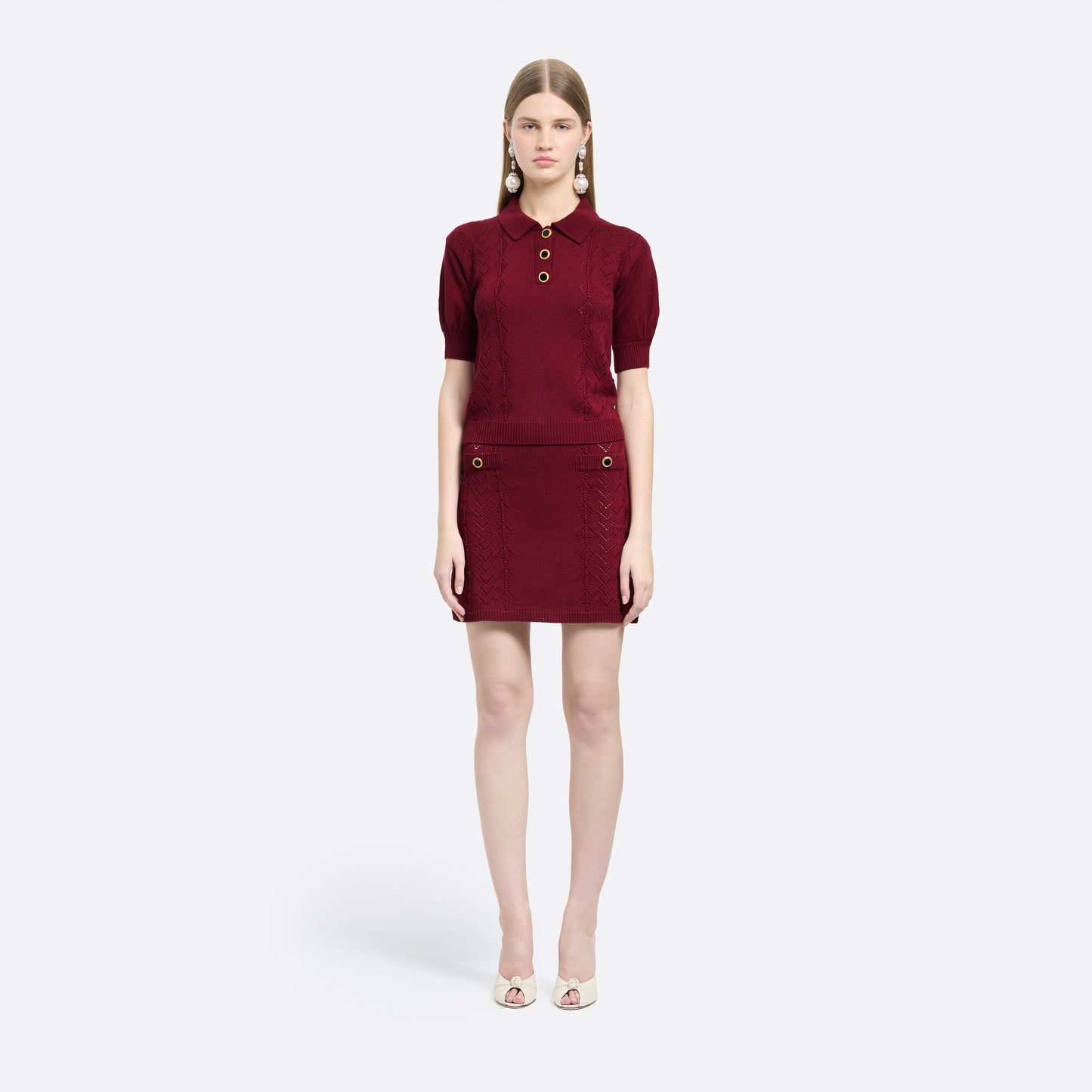 Bordeaux merino wool lace-knit mini skirt cut to a fitted silhouette with pocket details and black and gold-tone buttons.