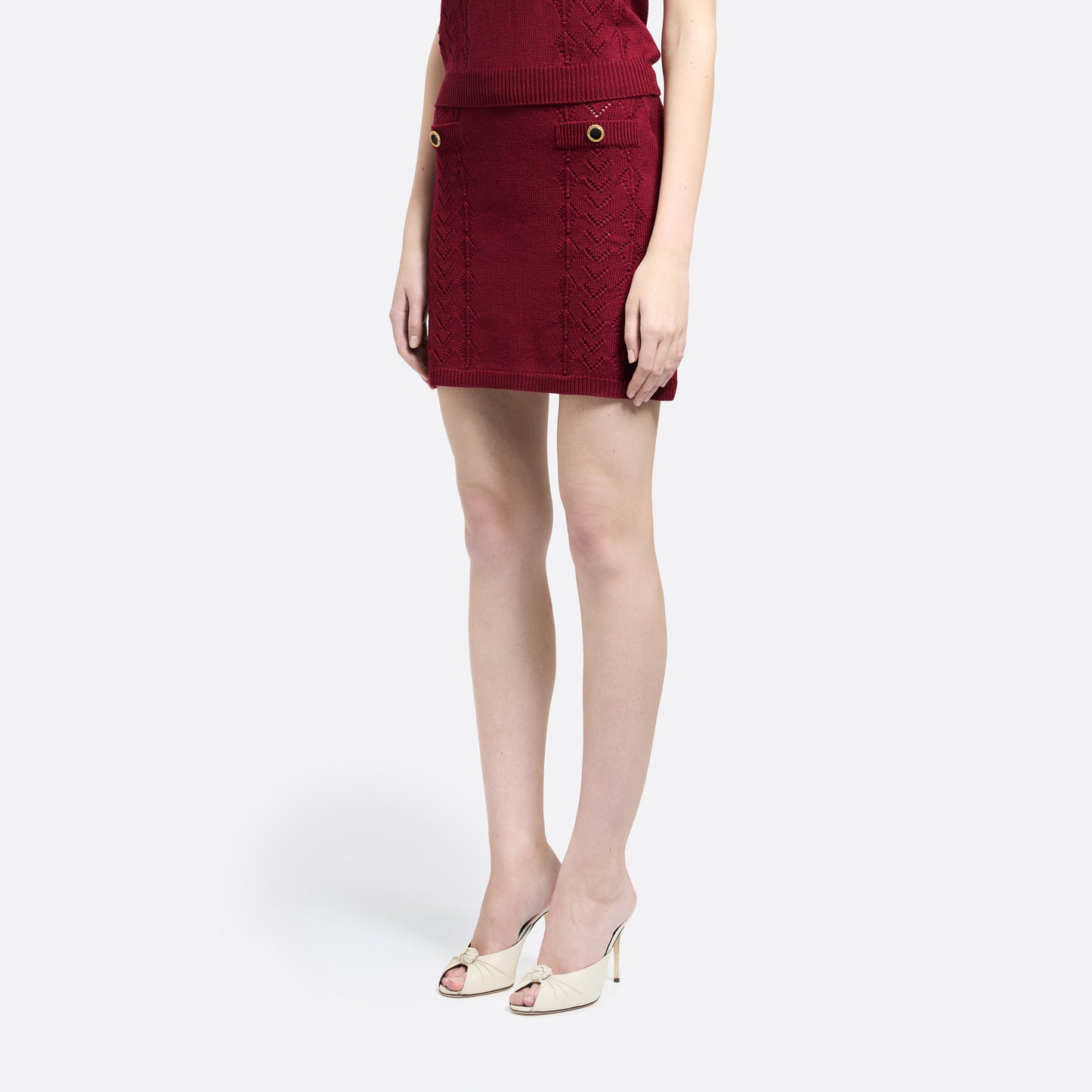 Bordeaux merino wool lace-knit mini skirt cut to a fitted silhouette with pocket details and black and gold-tone buttons.
