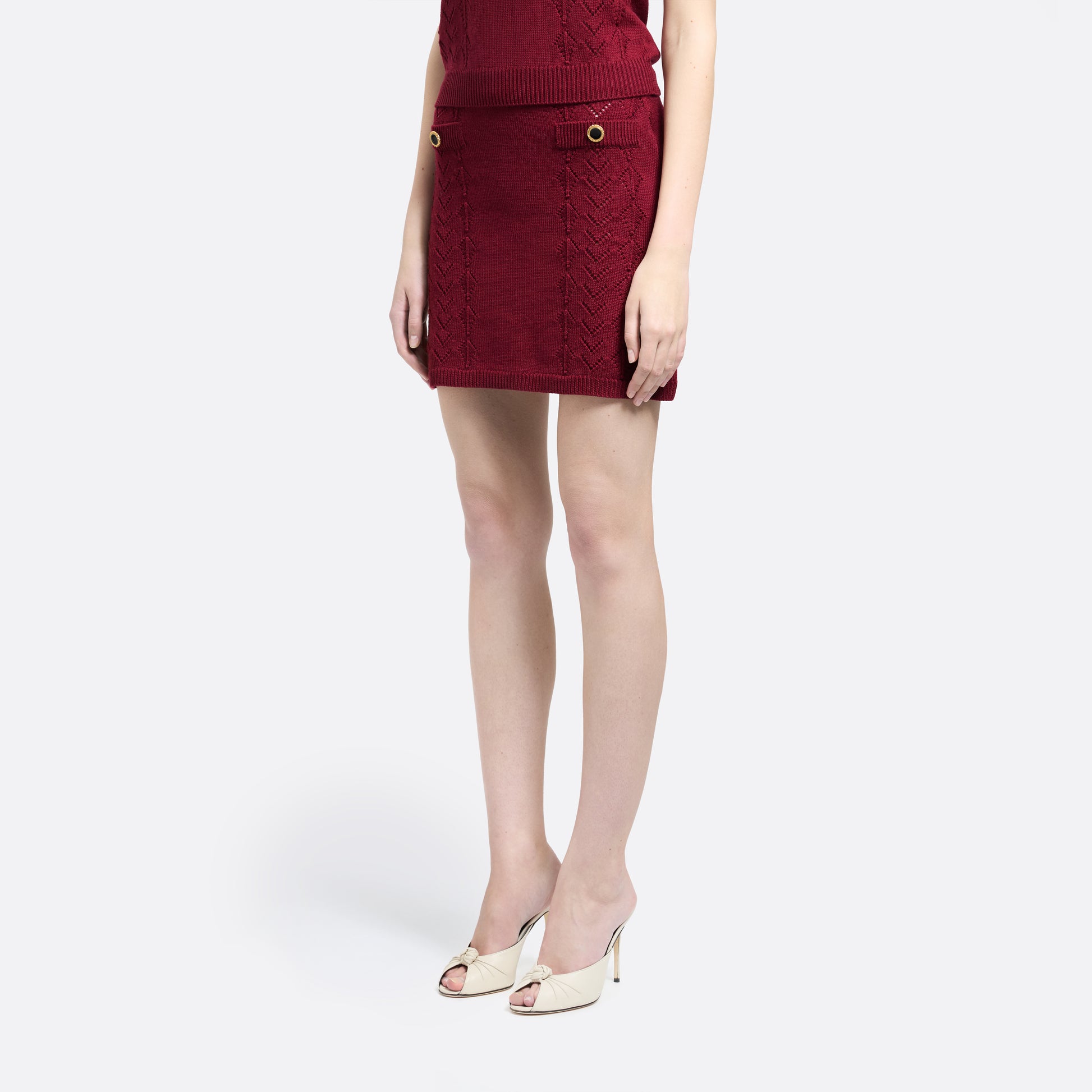 Bordeaux merino wool lace-knit mini skirt cut to a fitted silhouette with pocket details and black and gold-tone buttons.