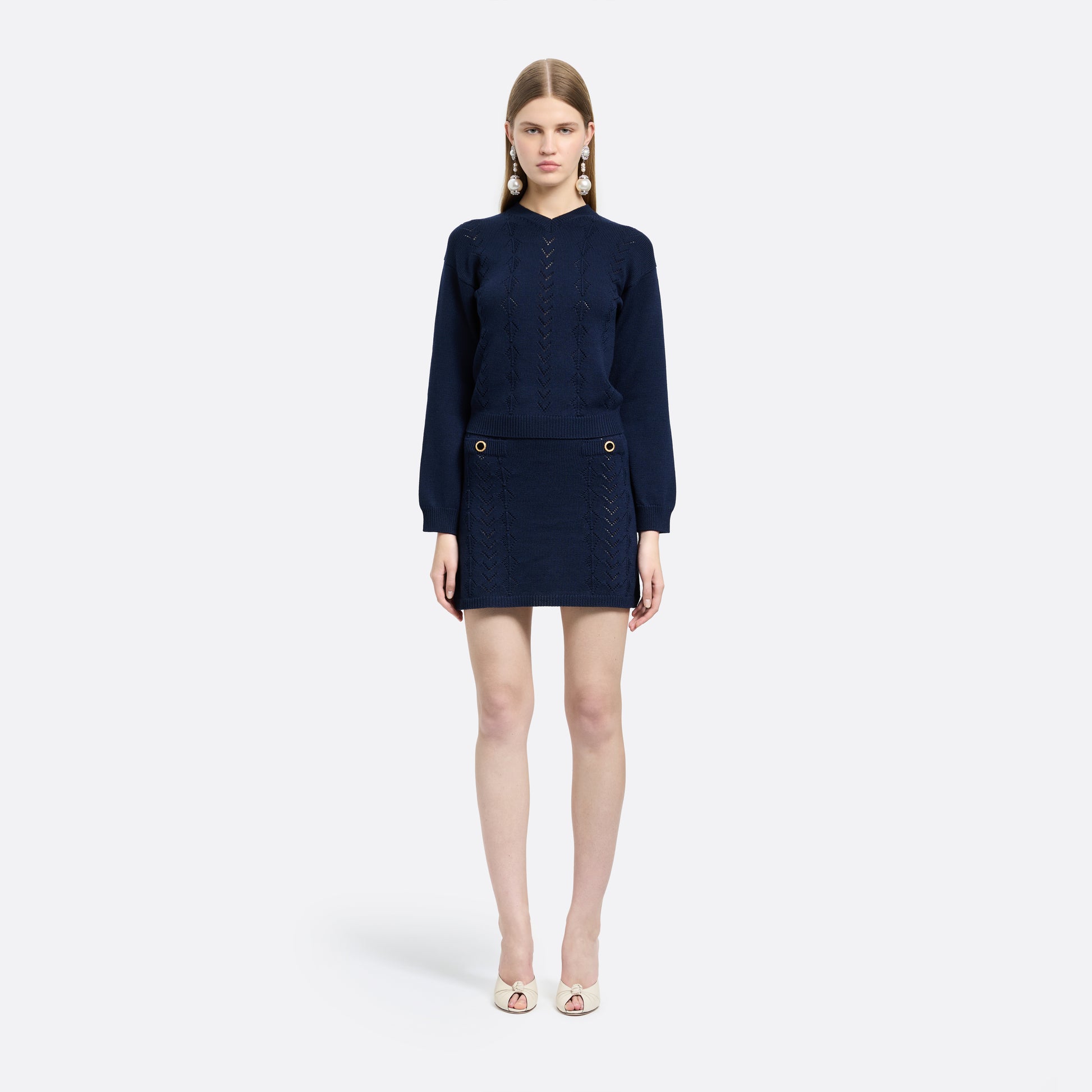 Navy-blue merino wool lace-knit mini skirt cut to a fitted silhouette with pocket details and black and gold-tone buttons.