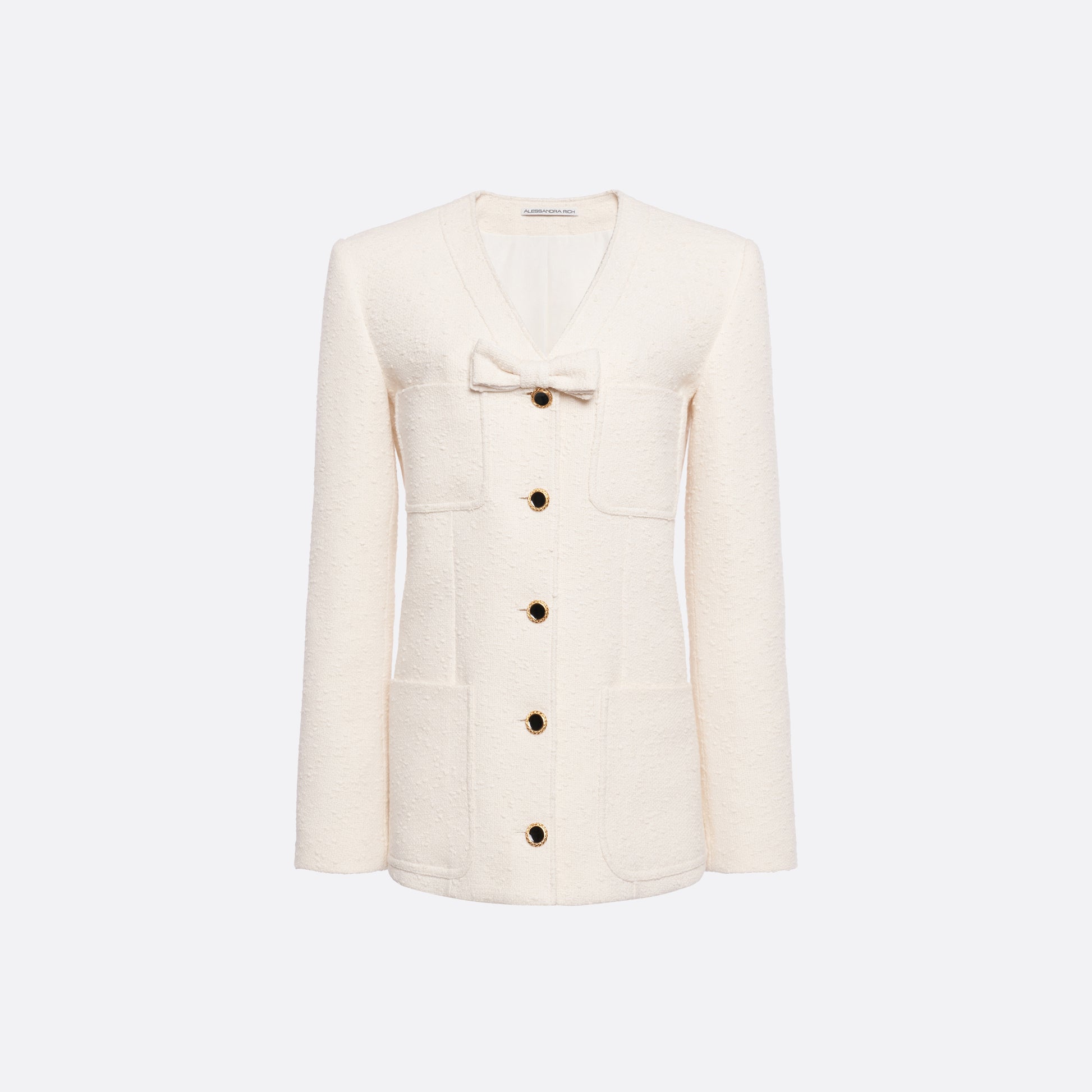 Ivory tweed bouclé jacket cut to a longline silhouette with a V-neckline and patch pockets. Finished with black and gold-tone buttons and a bow detail.