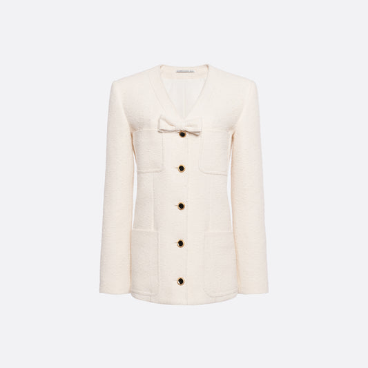 Ivory tweed bouclé jacket cut to a longline silhouette with a V-neckline and patch pockets. Finished with black and gold-tone buttons and a bow detail.