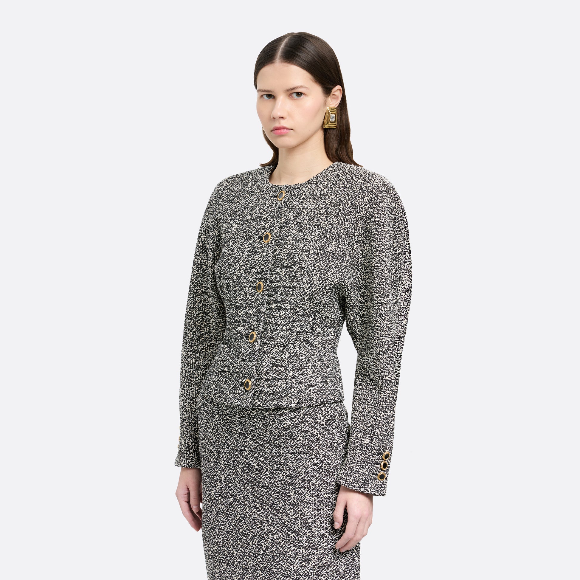 Black and white melange sequin tweed jacket cut in a cropped, boxy silhouette with defined shoulders and finished with black and gold-tone buttons.