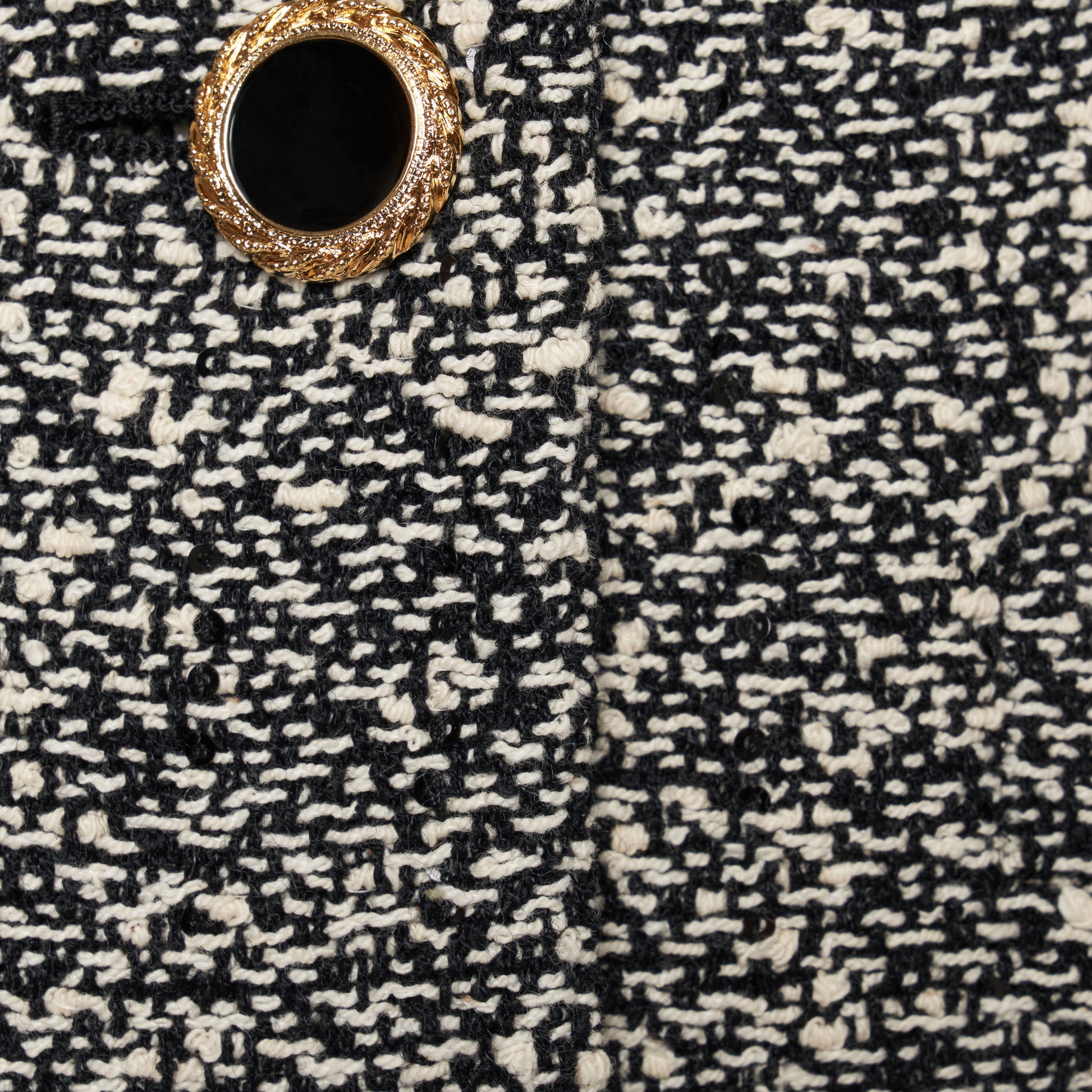 Black and white melange sequin tweed jacket cut in a cropped, boxy silhouette with defined shoulders and finished with black and gold-tone buttons.