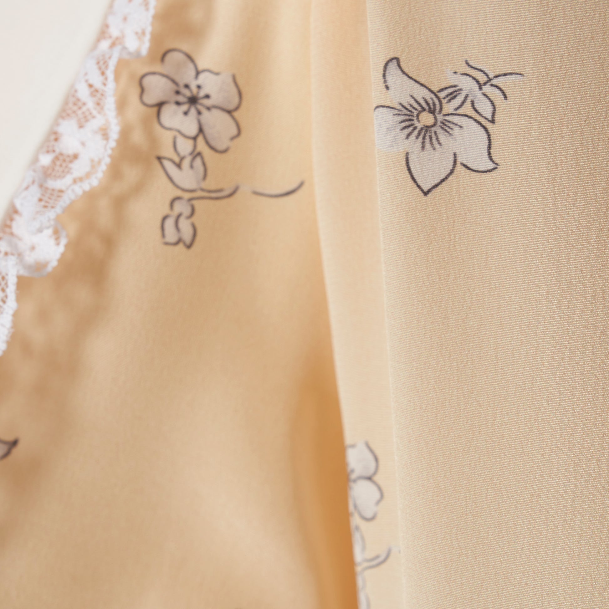 Pale yellow floral print silk crêpe de chine double-breasted midi dress with long sleeves, featuring a white lace-trimmed collar and belt.
