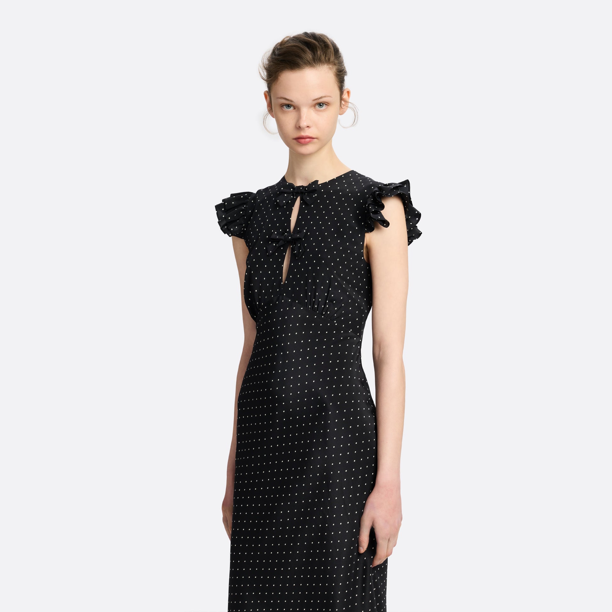 Ivory diamond print on black silk crêpe de chine sleeveless midi dress with bows, featuring keyhole cut-out and ruffled details.