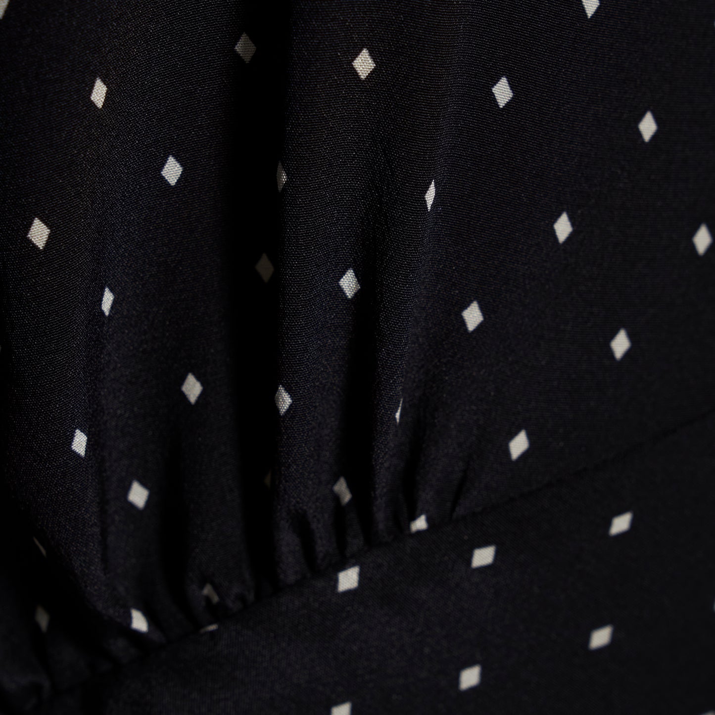 Ivory diamond print on black silk crêpe de chine sleeveless midi dress with bows, featuring keyhole cut-out and ruffled details.