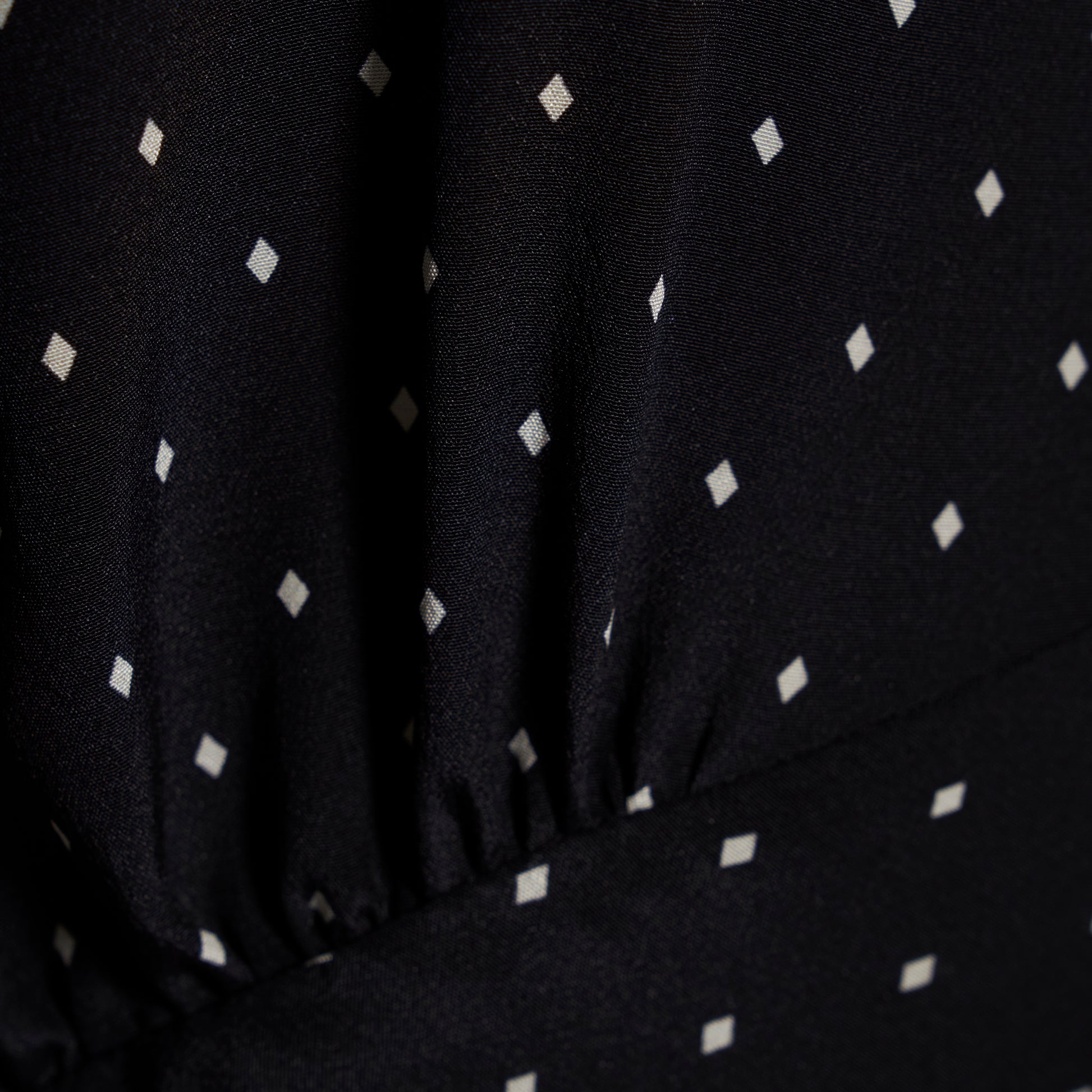 Ivory diamond print on black silk crêpe de chine sleeveless midi dress with bows, featuring keyhole cut-out and ruffled details.