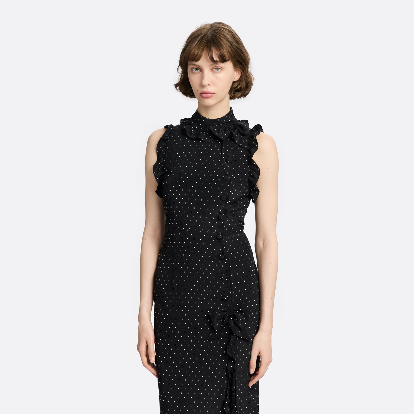Ivory diamond print on black silk crêpe de chine sleeveless midi dress with a high ruffled neckline, featuring button detail, side split and bow.
