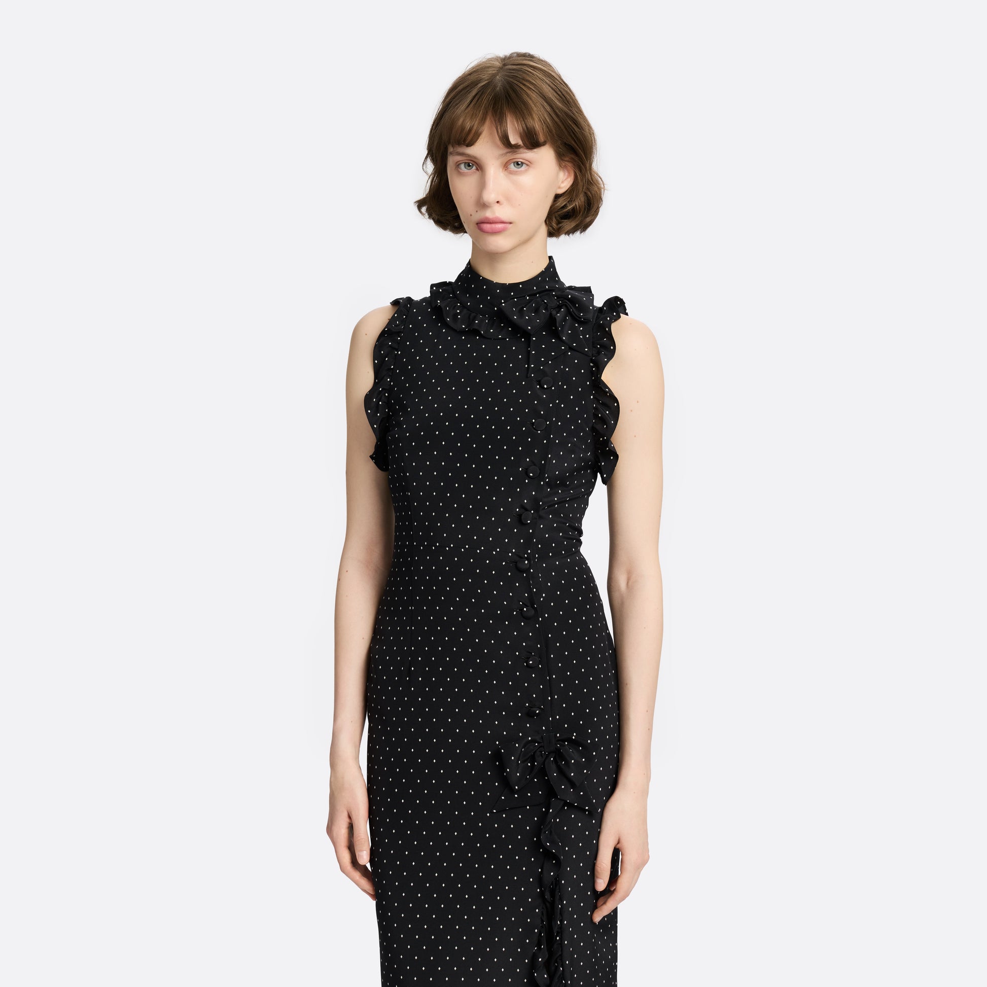 Ivory diamond print on black silk crêpe de chine sleeveless midi dress with a high ruffled neckline, featuring button detail, side split and bow.
