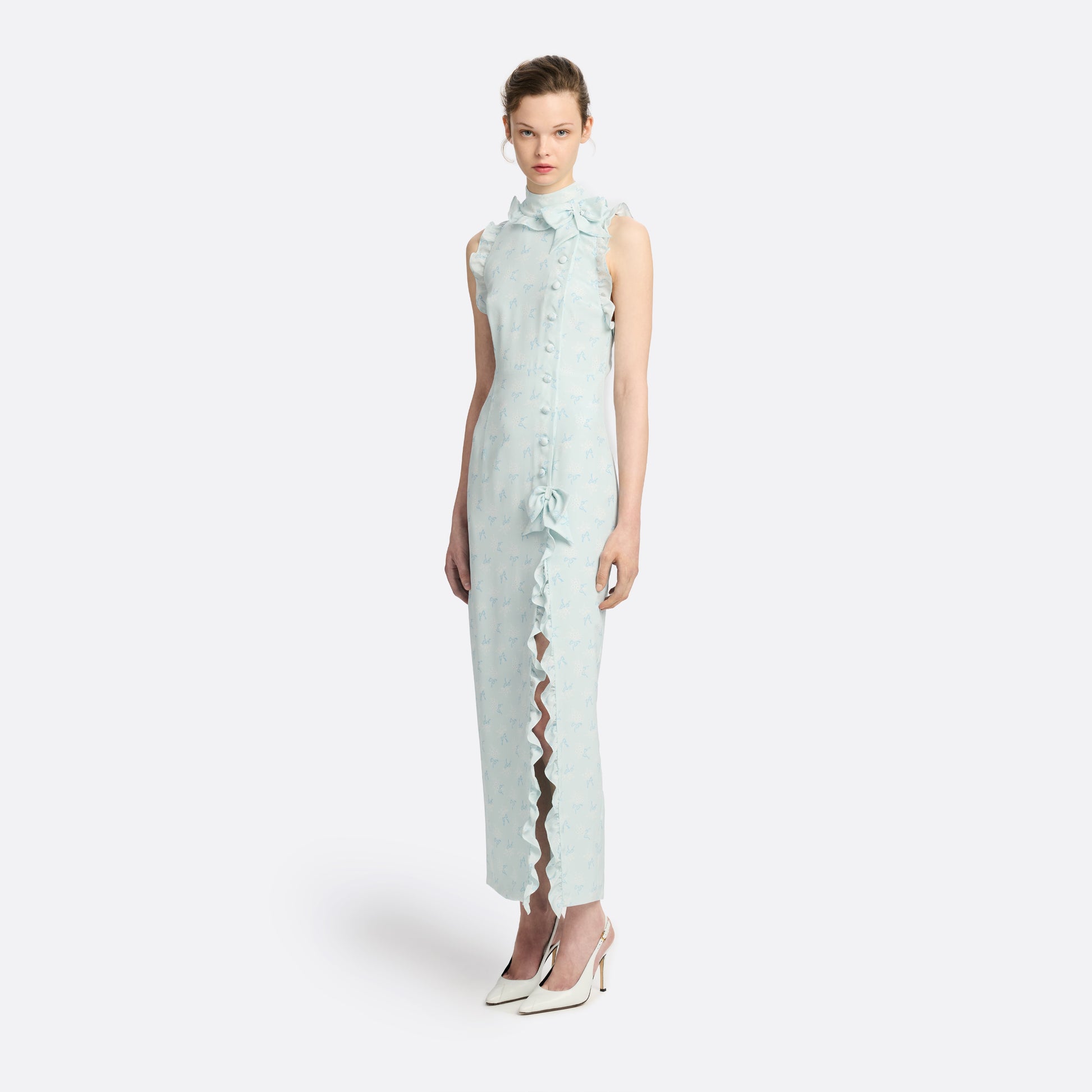 Pale blue floral print silk crêpe de chine sleeveless midi dress with a high ruffled neckline, featuring button detail, side split and bow.