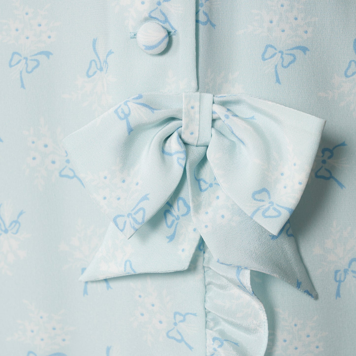Pale blue floral print silk crêpe de chine sleeveless midi dress with a high ruffled neckline, featuring button detail, side split and bow.