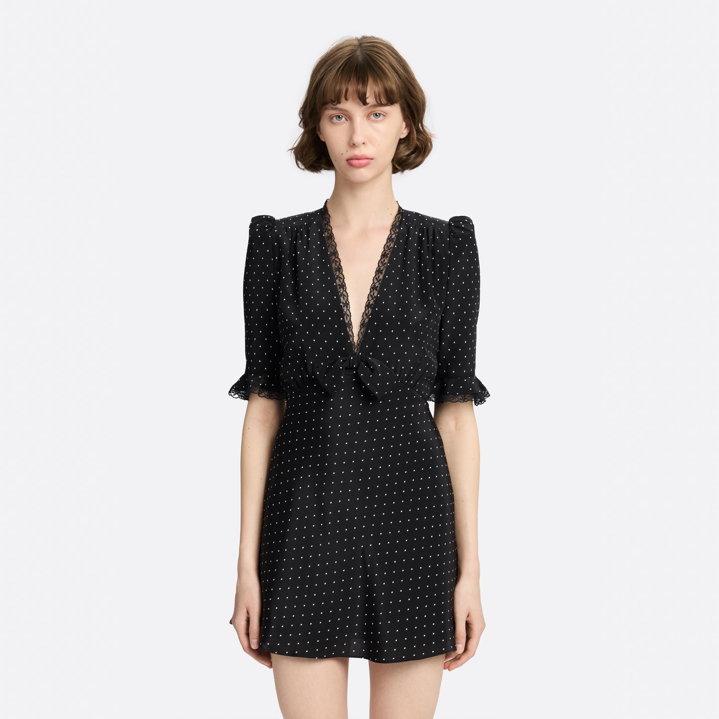 Ivory diamond print on black silk crêpe de chine mini dress with a V neckline and short sleeves, featuring lace trims and a bow.