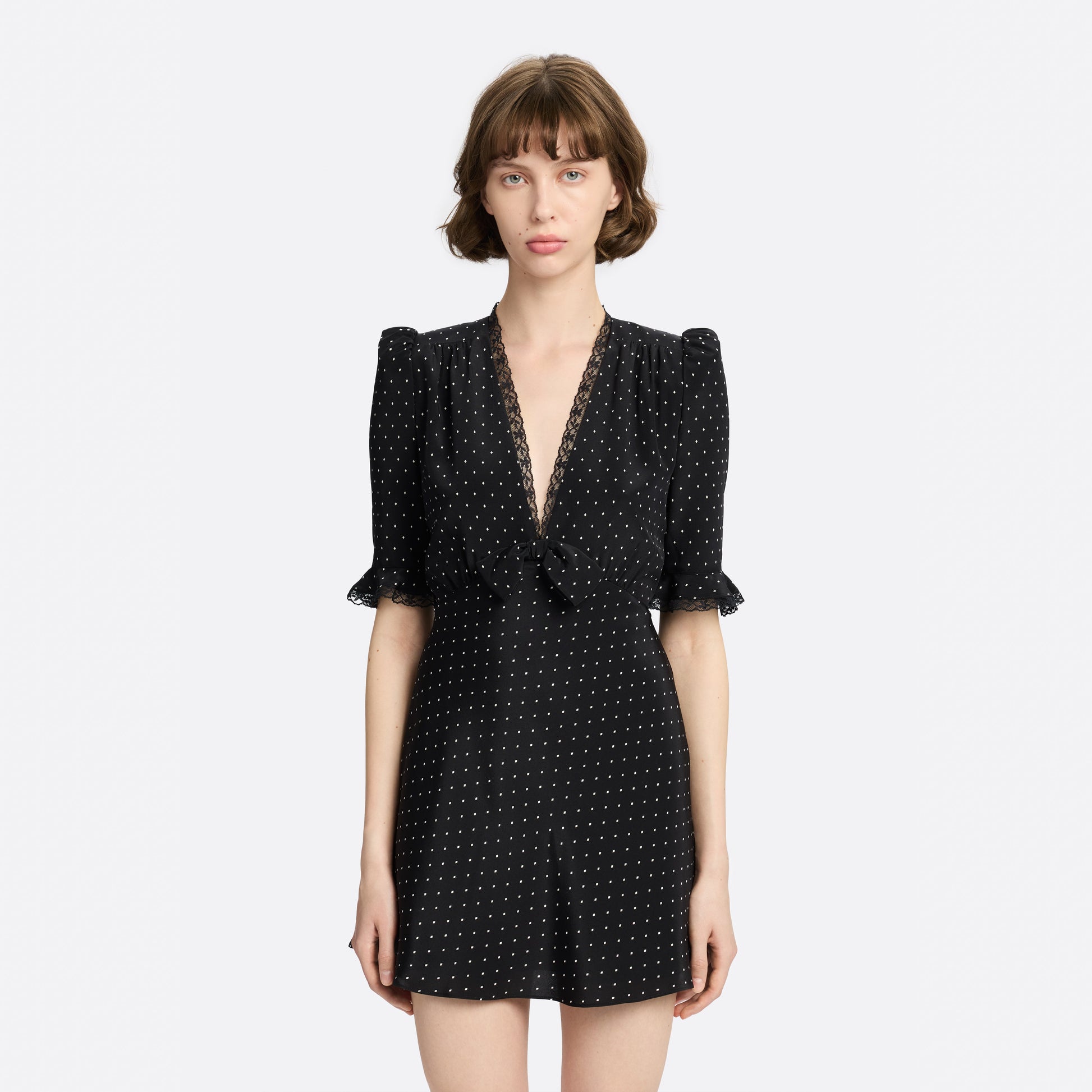 Ivory diamond print on black silk crêpe de chine mini dress with a V neckline and short sleeves, featuring lace trims and a bow.