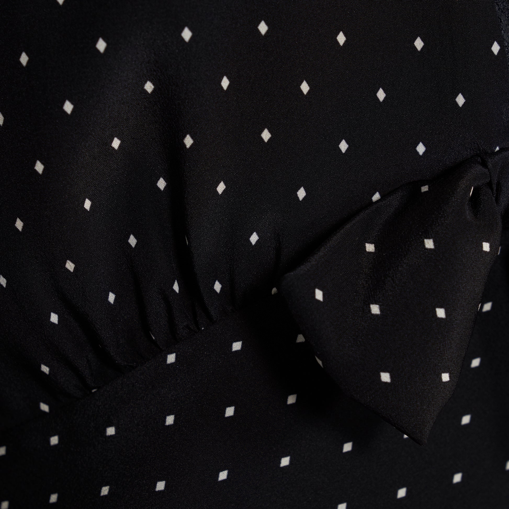 Ivory diamond print on black silk crêpe de chine mini dress with a V neckline and short sleeves, featuring lace trims and a bow.