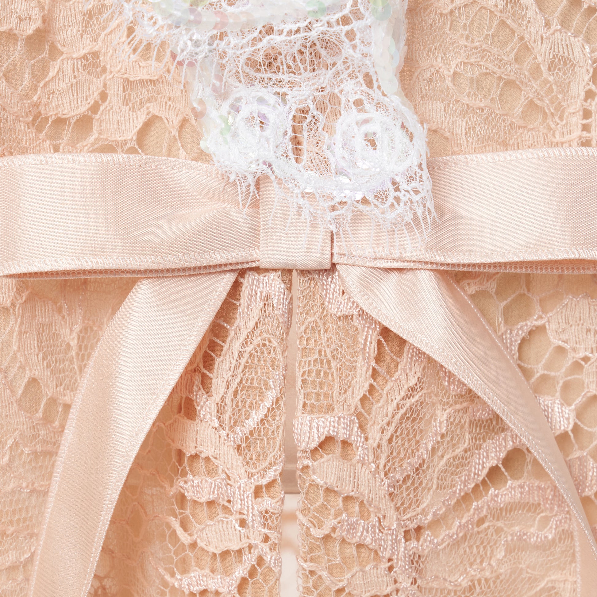 Nude lace slip dress cut to a fitted silhouette with delicate spaghetti straps and a V-neckline detailed with a sequin-embroidered lace volant. Finished with silk satin bows and a front split.

Look 33 – Fall Winter 2026 Lookbook