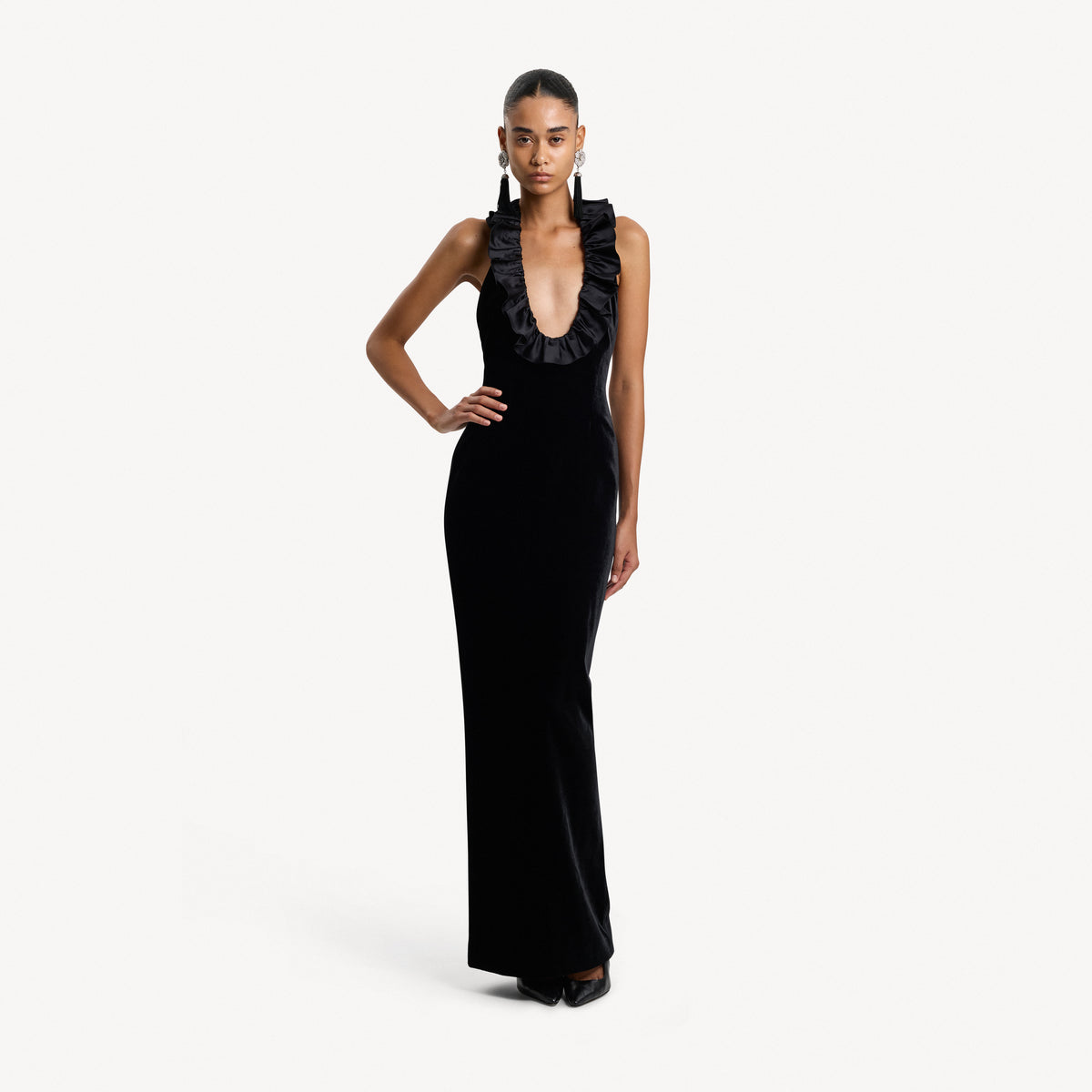 Black velvet evening dress featuring an open back and a deep neckline with a silk ruffle trim.