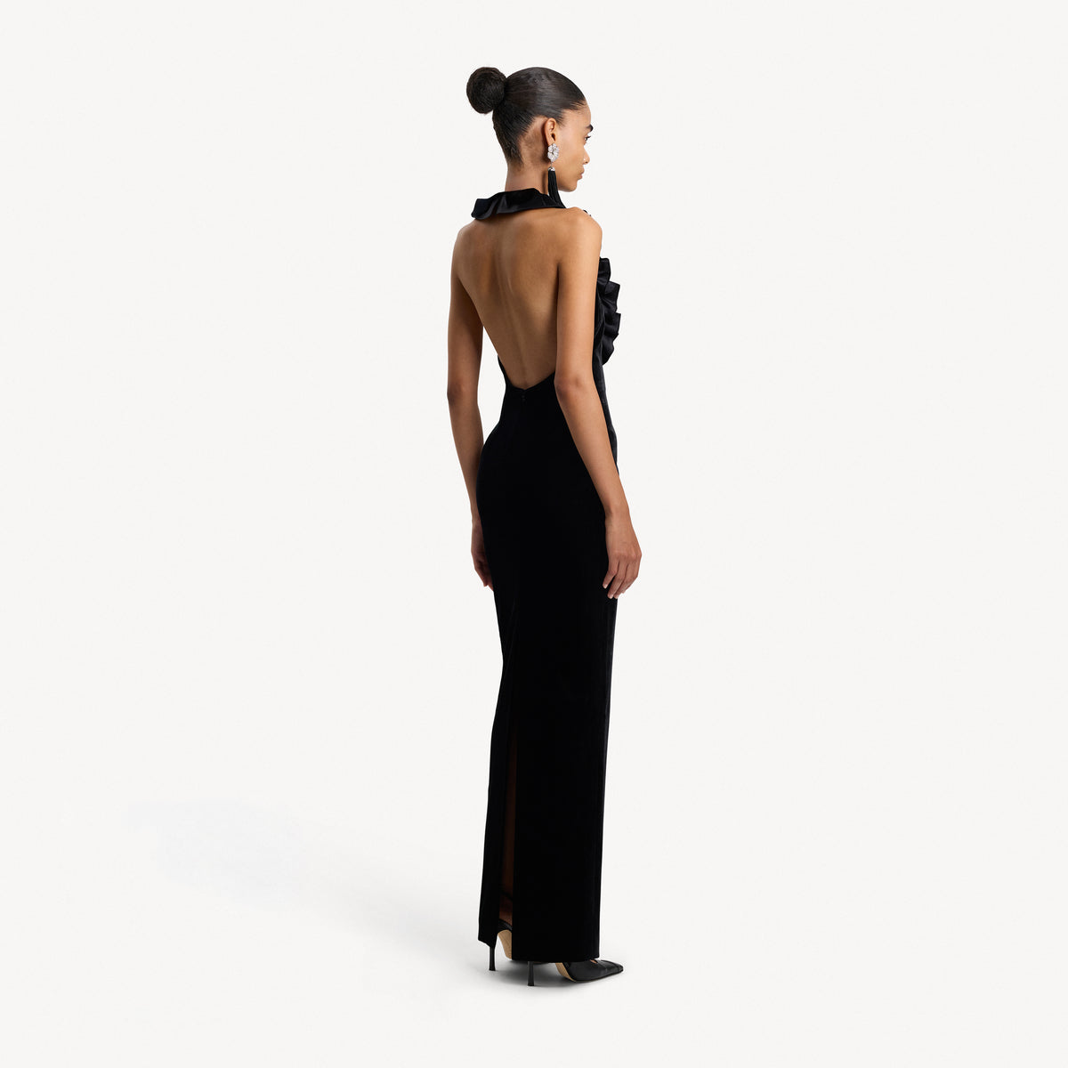 Black velvet evening dress featuring an open back and a deep neckline with a silk ruffle trim.