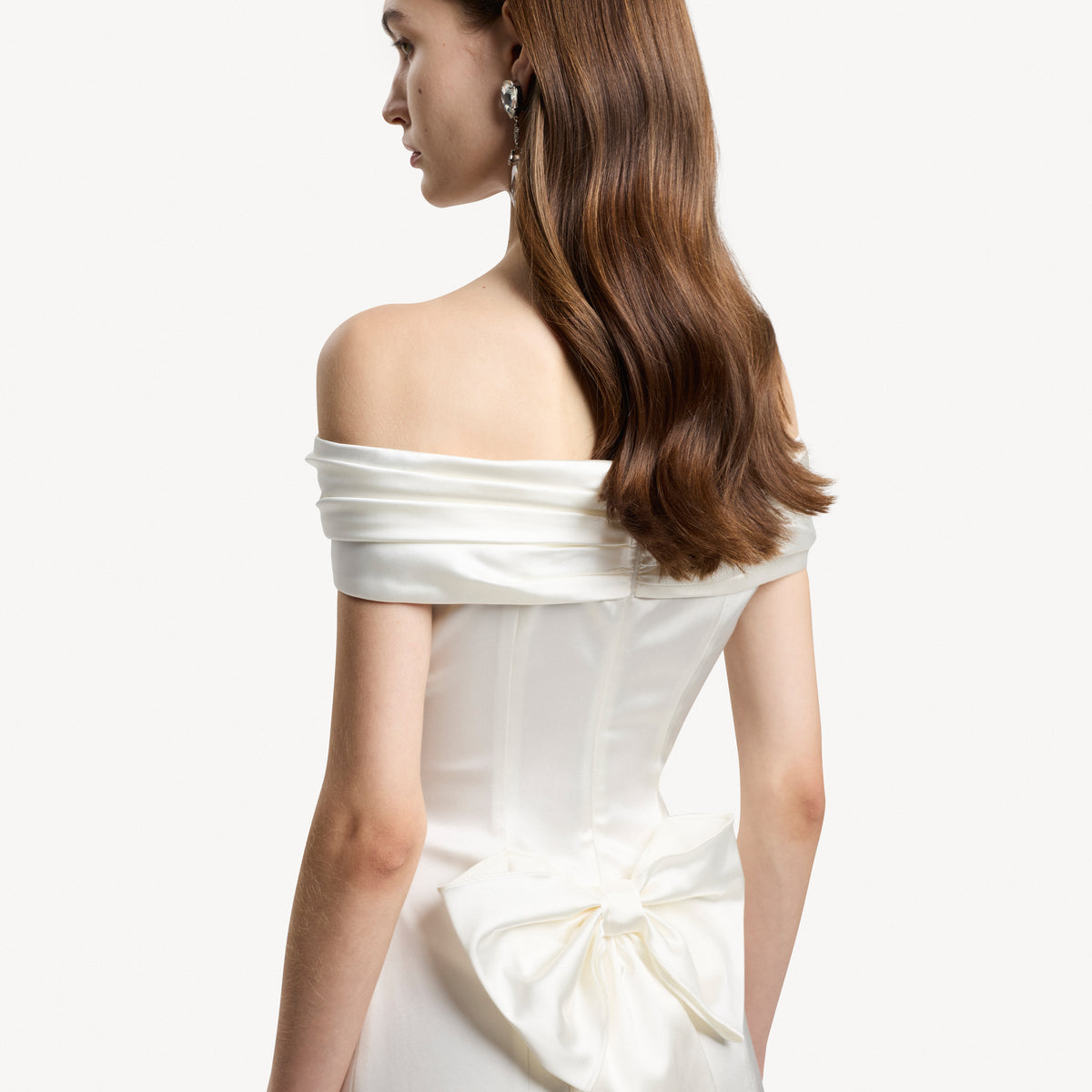 White stretch duchesse mini dress with a gathered off-shoulder neckline and bow details.
