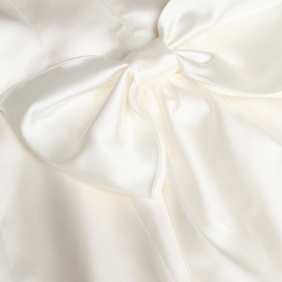 White stretch duchesse mini dress with a gathered off-shoulder neckline and bow details.
