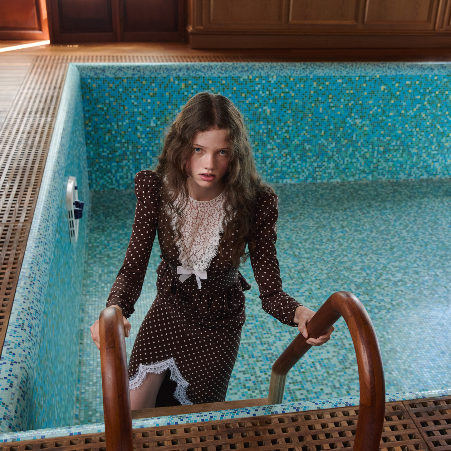 White polka dot print on brown crêpe de chine midi dress with long sleeves and lace detail, featuring a ruffle trim and a lace front slit.